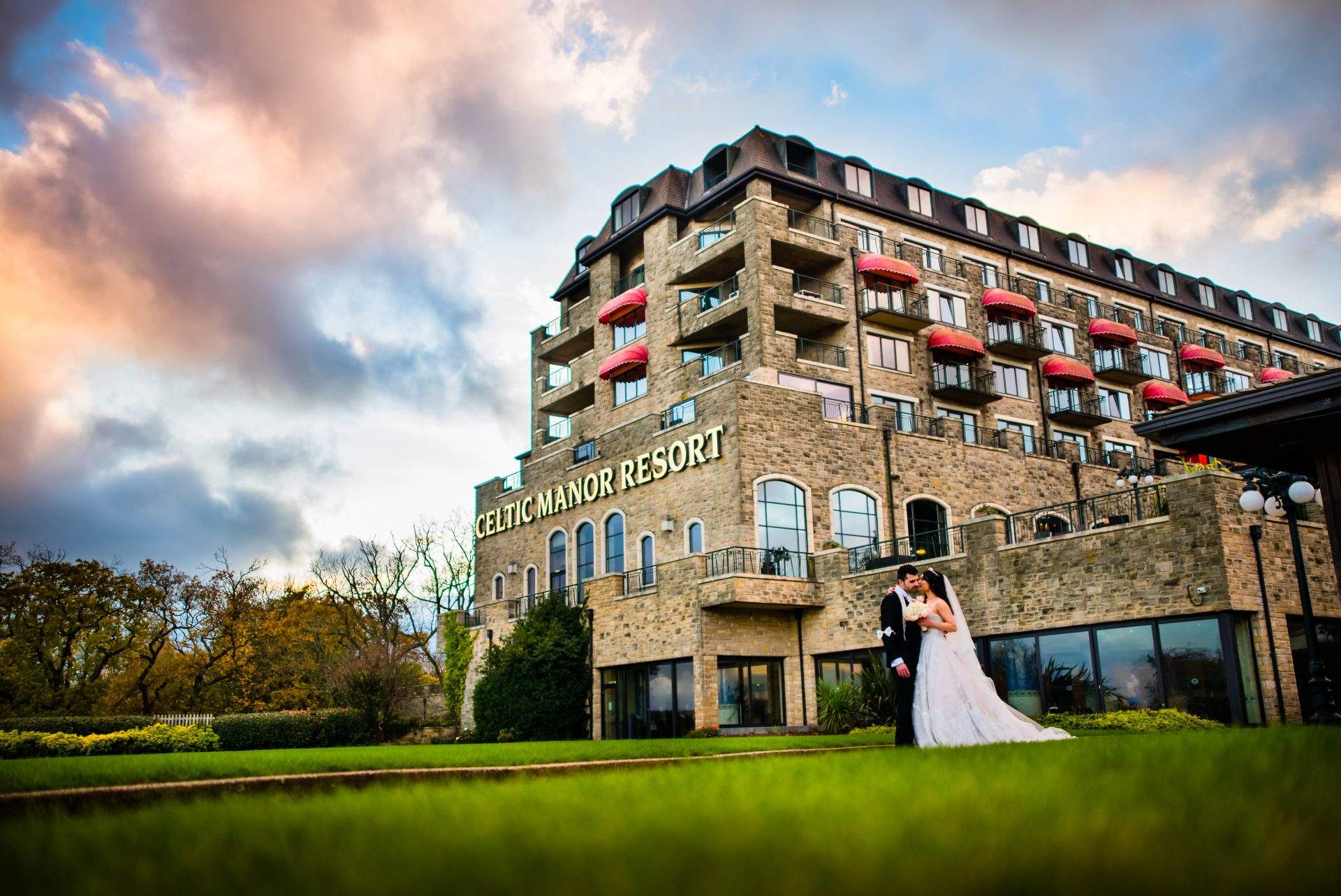Bride and groom standing in front of the Celtic Manor Hotel on there wedding day photo shoot