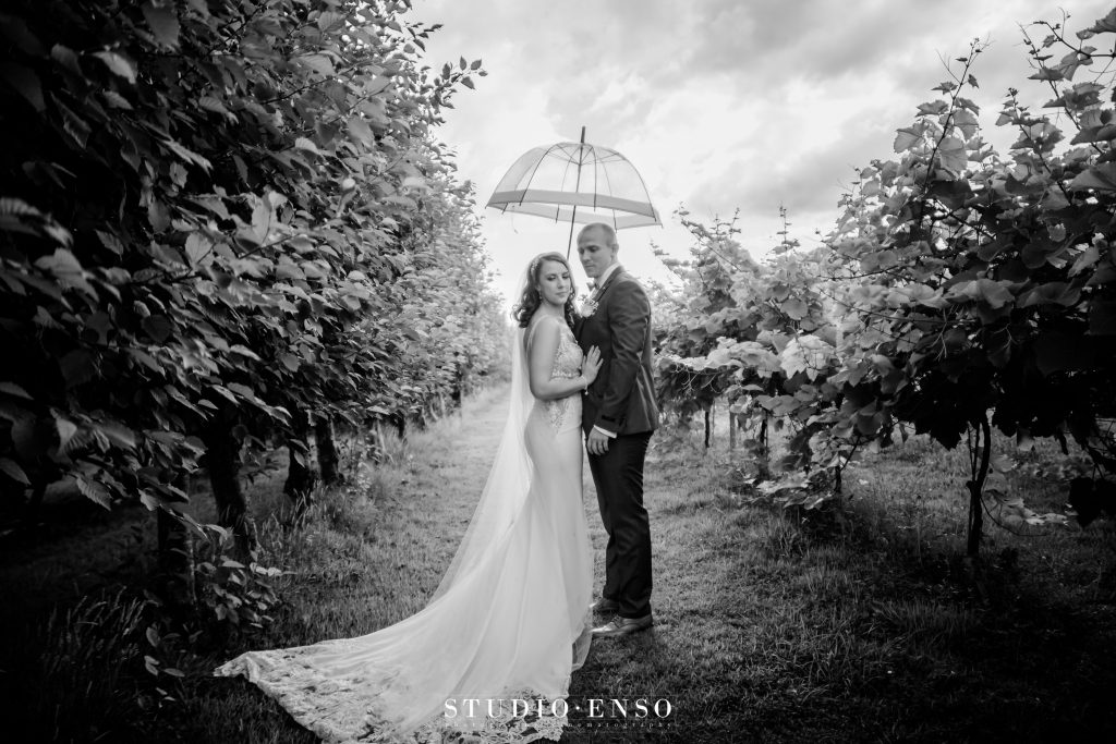 Bride and Groom under an umbrella on their wedding day at Llanerch Vineyard